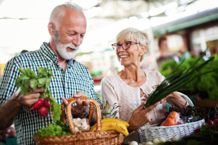 Happy senior couple buying fresh food at the market